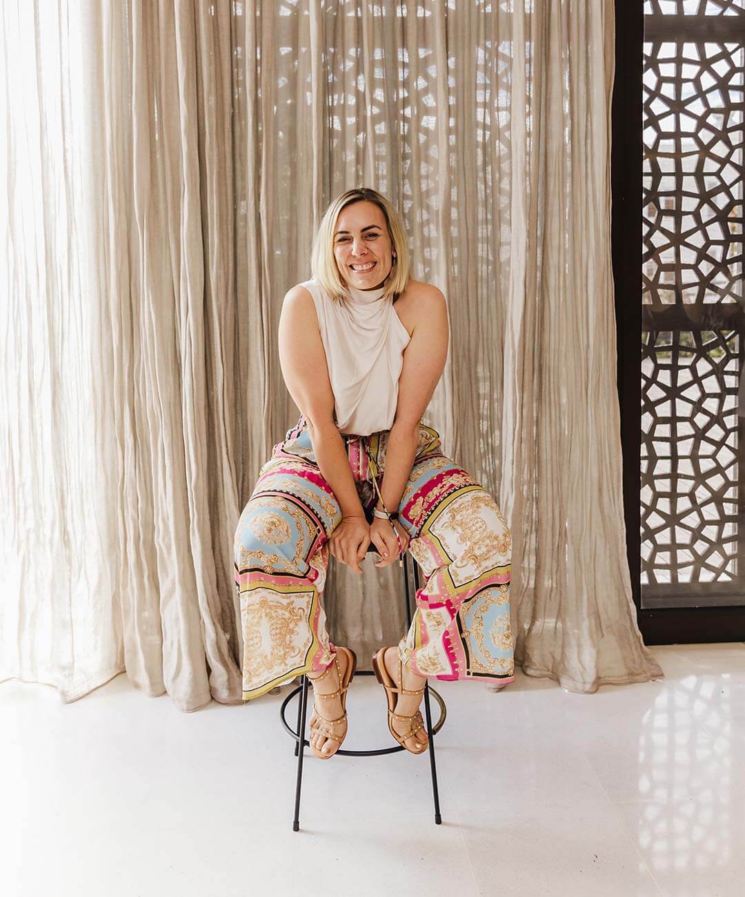 Renee Mariette, owner and copywriter at Make Words Work, sirtting on a stool at a networking event.